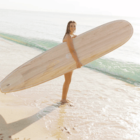 Thumbnail for A Beginner Surfer carrying a Surfboard Trading Co. Just The Tip Noserider Longboard - Paulownia Gloss | Beginner-Friendly Longboard