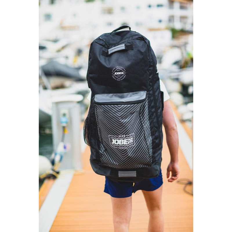 A man carrying his SUP in Jobe Aero Inflatable Paddle Board SUP Travel Bag - Black 