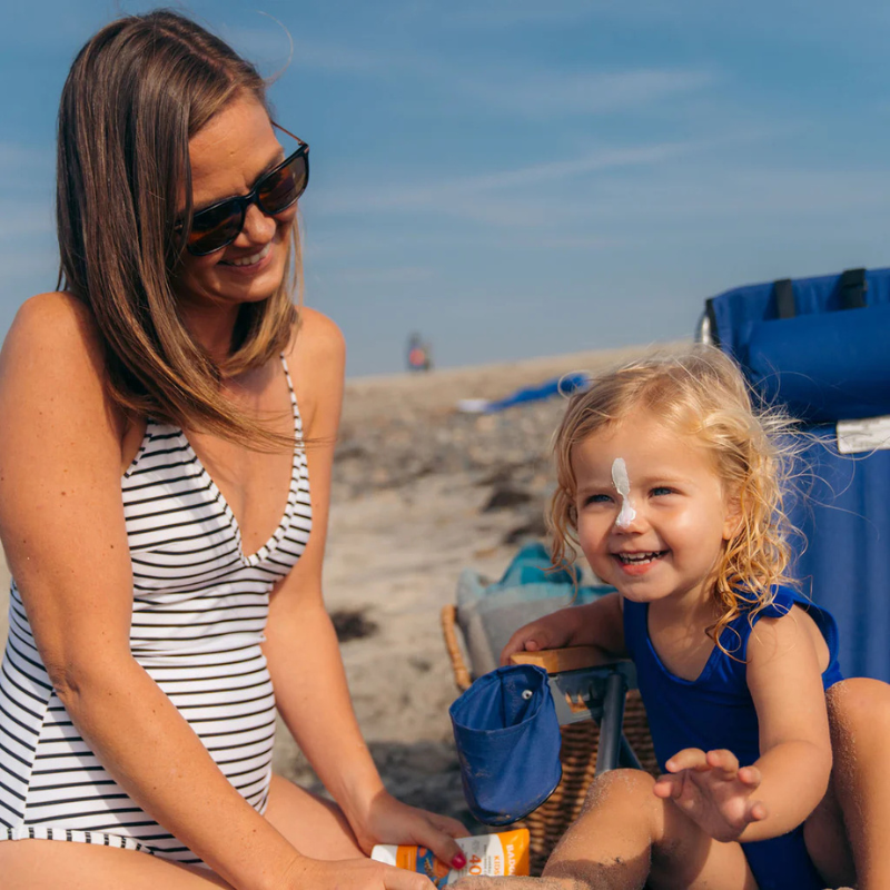 A mother applying Badger SPF 40 Kids 2.9 oz Mineral Sunscreen Cream on her child