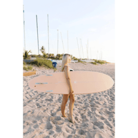 Thumbnail for An intermediate surfer carrying a Surfboard Trading Co. ANY DAY Mid Length EPS Surfboard – Peach 
