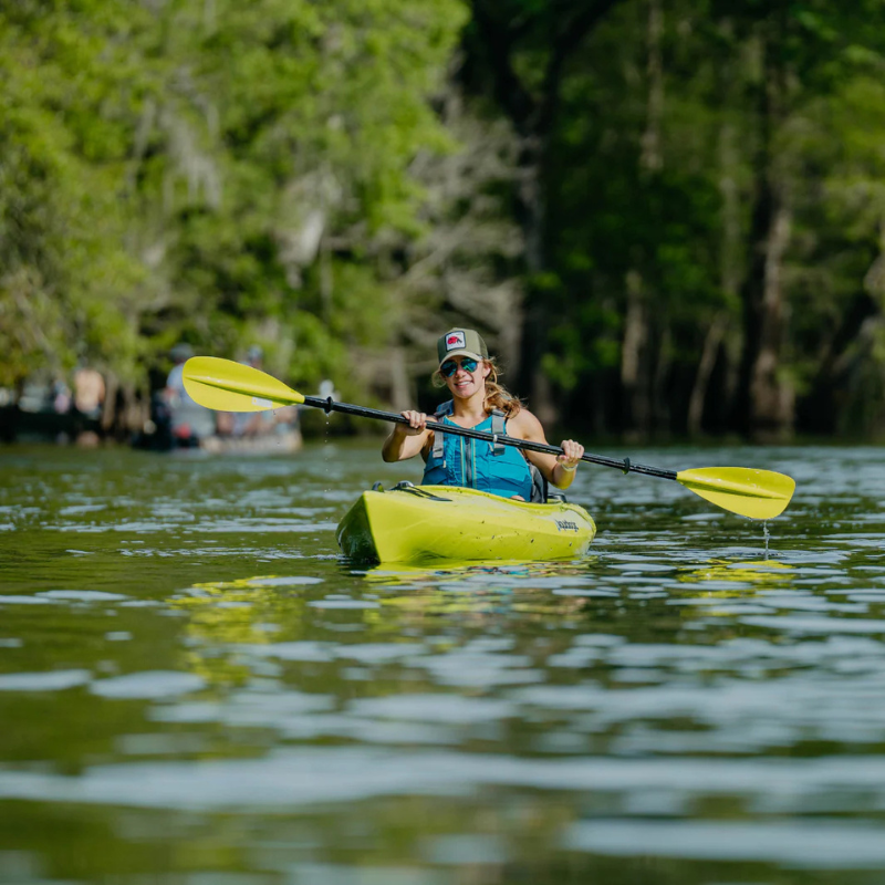 An woman using a green Bending Branches Sunrise Glass 2‑Piece Kayak Paddle