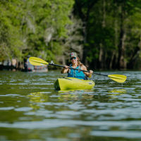 Thumbnail for An woman using a green Bending Branches Sunrise Glass 2‑Piece Kayak Paddle