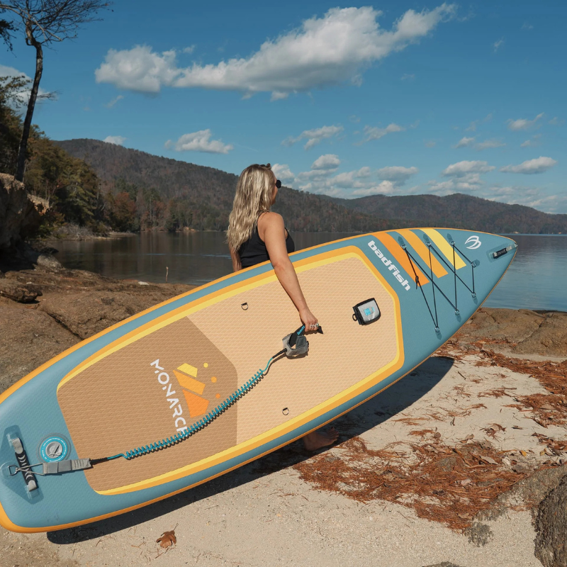 A person carrying Badfish 11' Monarch 2026 Inflatable Paddleboard | All-Around SUP 
