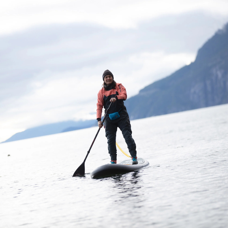 A person with Mustang Survival Minimalist Manual Inflatable Belt Pack- Azure on an iSUP