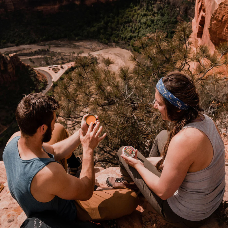 Two people using Badger Sore Muscle Rub Tin - Natural & Organic