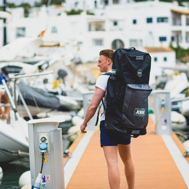 a man carrying Jobe Aero Inflatable Paddle Board black SUP Travel Bag