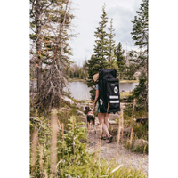 Thumbnail for a man carrying POP Board Co 10’6” Royal Hawaiian Stand Up Paddle Board - Pink/Black in a backpack