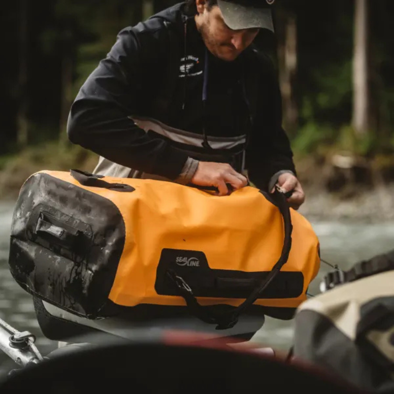 a man carrying a SealLine PRO Zip 40L Dry Duffle Bag Orange