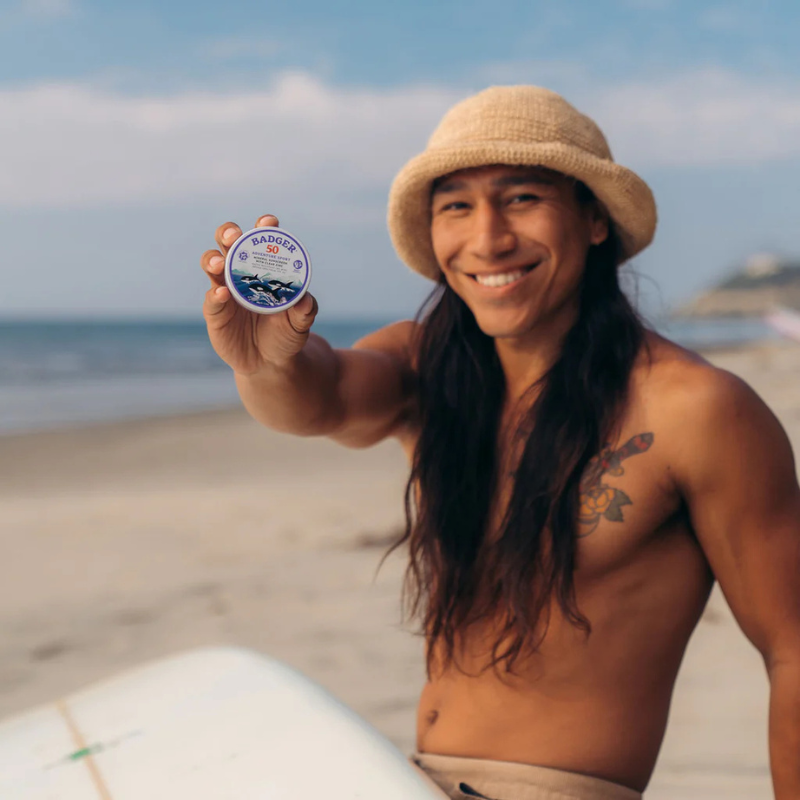 a man holding a Badger SPF 50 Adventure 2.4 oz Mineral Sunscreen Tin