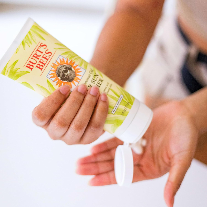 a person applying Burt’s Bees 6 oz Aloe & Coconut Oil After Sun Soother Lotion on hand