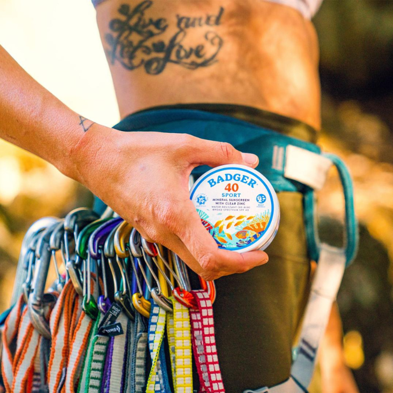 a person holding a tin can of Badger SPF 40 Sport 2.4 oz Mineral Sunscreen 