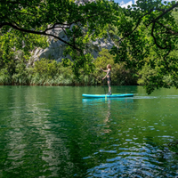 Thumbnail for distant view of a person riding a Jobe Aero Nera 10’6” Inflatable Paddle Board iSUP